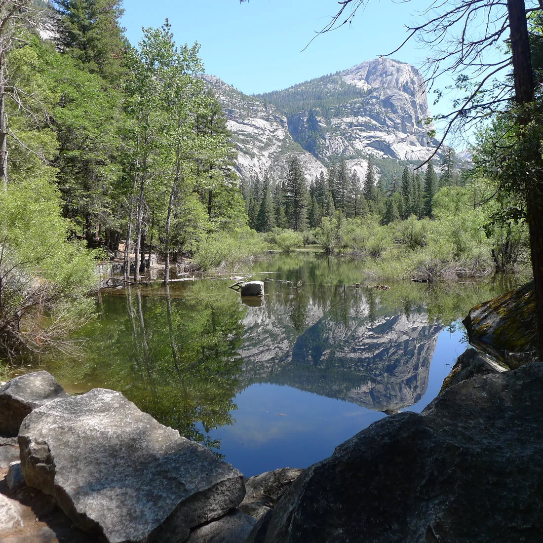 Granite cliffs and trees reflected in water in Yosemite Valley