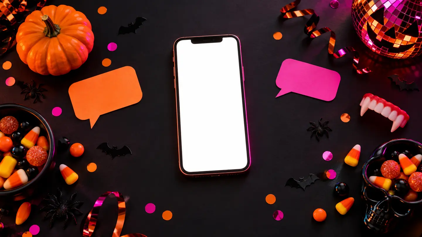 Blank smartphone with Halloween candy and colorful speech-bubble cards for short funny quotes